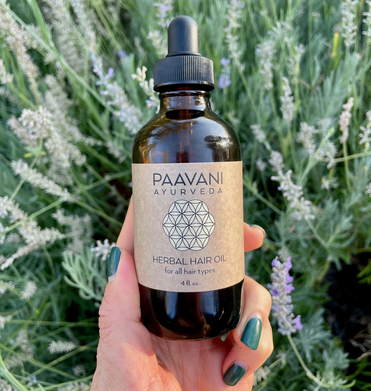 Hand holding the Ayurvedic Herbal Hair Oil bottle against a lush green background – Organic hair care solution.